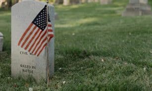 A gravestone with an American flag in a cemetery, honoring a civil war veteran.
