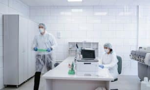 Researchers conducting experiments in a clean, modern laboratory environment wearing protective gear.