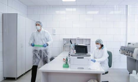 Researchers conducting experiments in a clean, modern laboratory environment wearing protective gear.