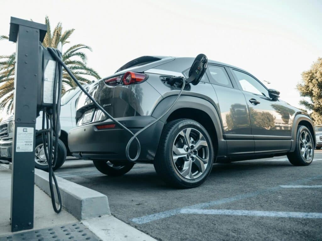 Modern electric vehicle charging at an outdoor station in daylight.