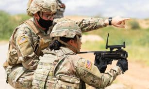 Two US soldiers engage in outdoor combat training, focusing on weapon proficiency.
