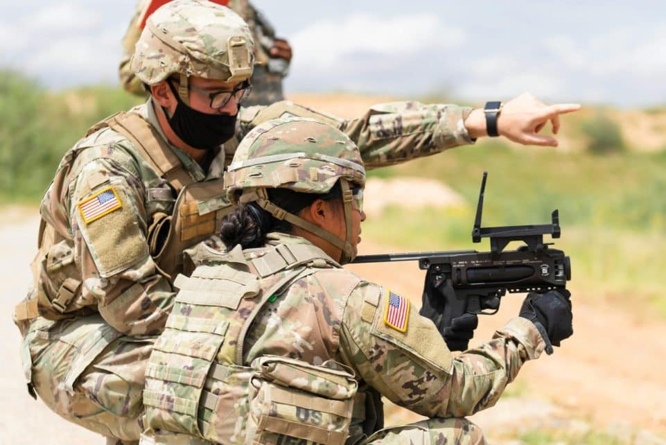 Two US soldiers engage in outdoor combat training, focusing on weapon proficiency.