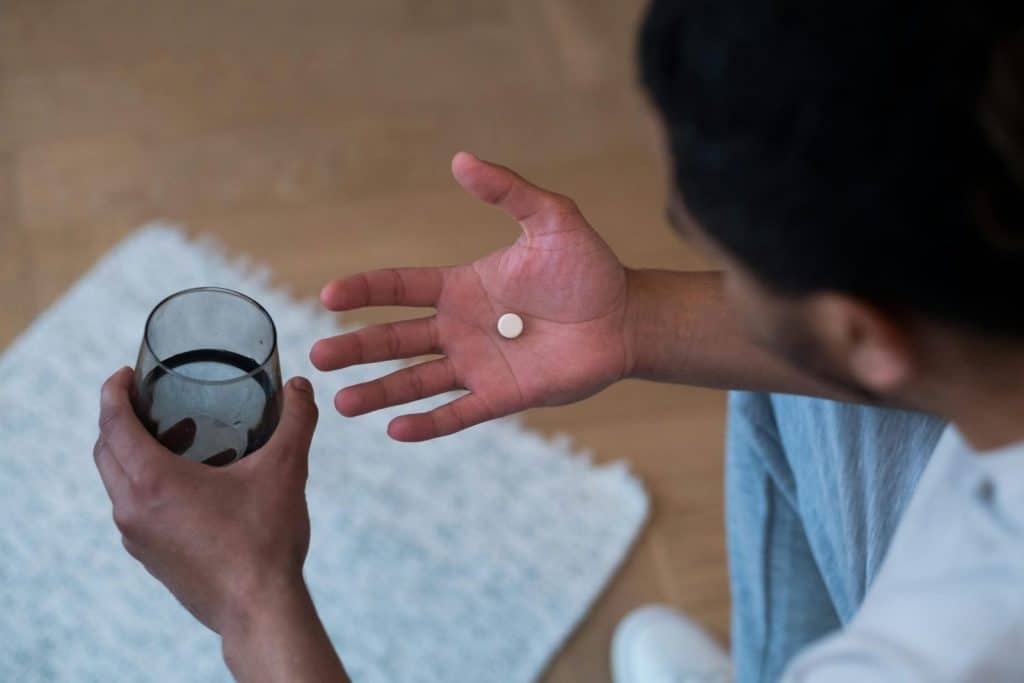 Close-up of a man about to take medication with water, indoors.
