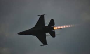 Dynamic F-16 jet showcasing an afterburner flame against a dusky sky.