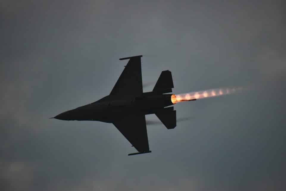 Dynamic F-16 jet showcasing an afterburner flame against a dusky sky.