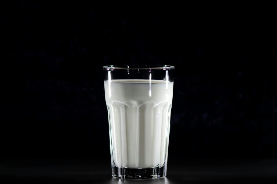 A glass of fresh milk against a black background, emphasizing simplicity and nutrition.