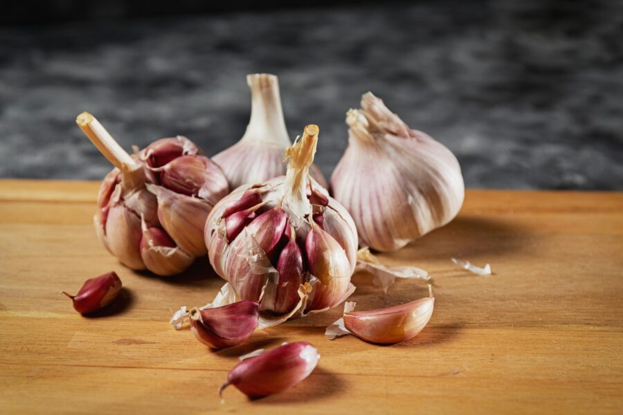 Close-up of fresh garlic bulbs and cloves on a wooden cutting board.