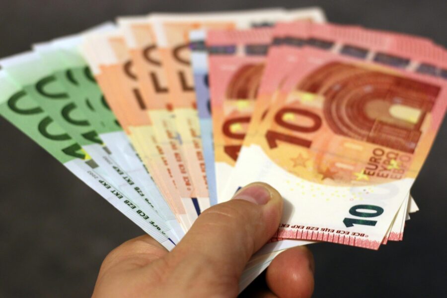 A fan of euro banknotes in various denominations held in a hand.