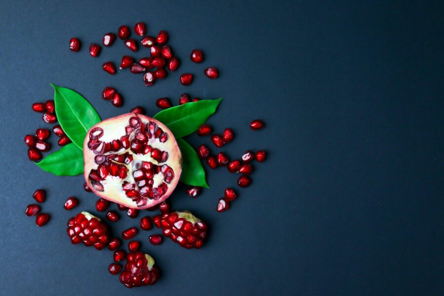 Top view of pomegranate and seeds on blue surface with copy space.