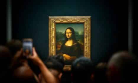 A group of people taking pictures of a painting