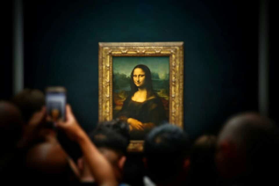 A group of people taking pictures of a painting