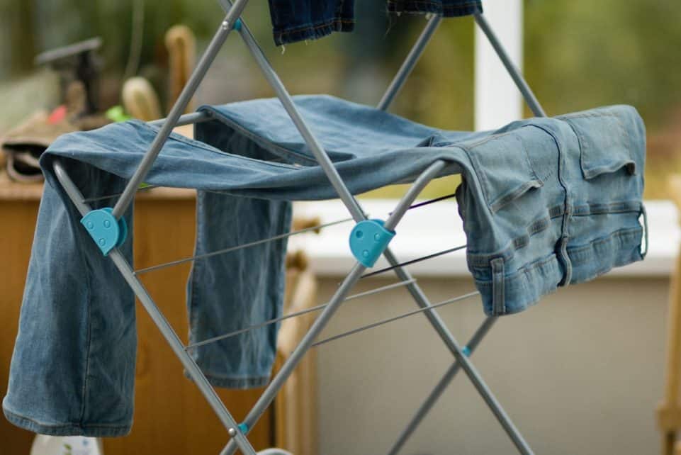 An ironing board with clothes on it in front of a window
