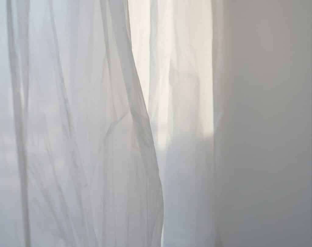 a white curtain with a cat sitting on top of it