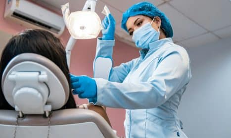 a woman getting her teeth brushed by a dentist