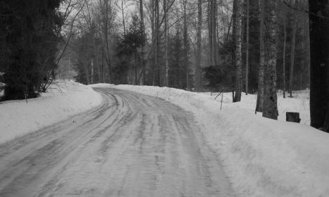 a snow covered road in the middle of a forest