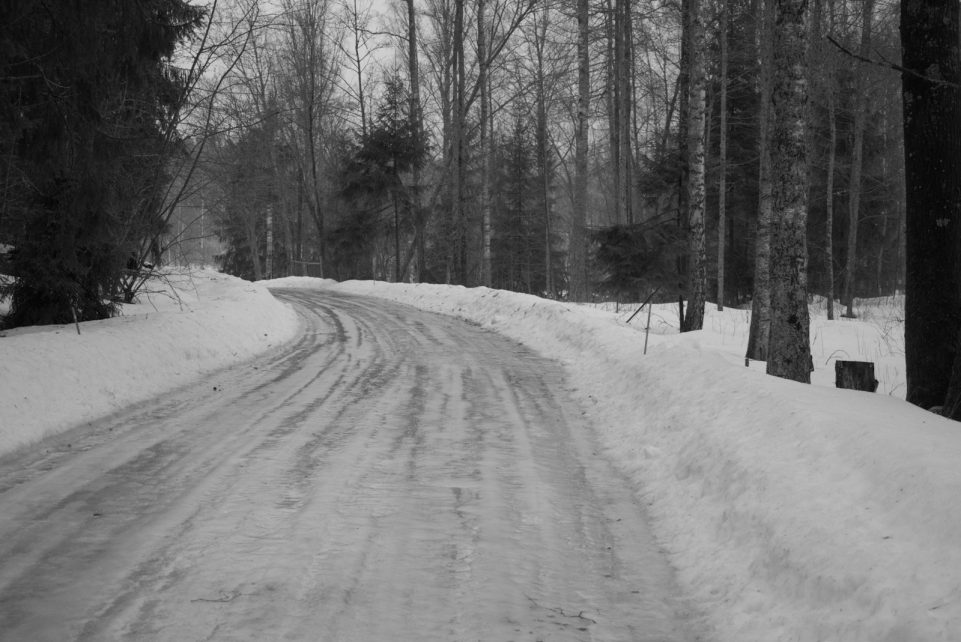 a snow covered road in the middle of a forest