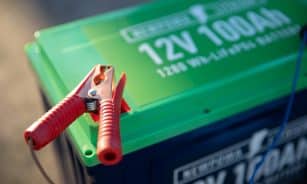 a red and green battery with a pair of pliers attached to it