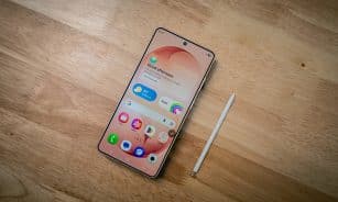 A smartphone with a stylus rests on a wooden surface.