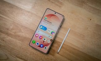 A smartphone with a stylus rests on a wooden surface.