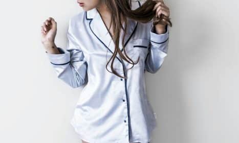 woman in white and black button-up coat leaning on wall