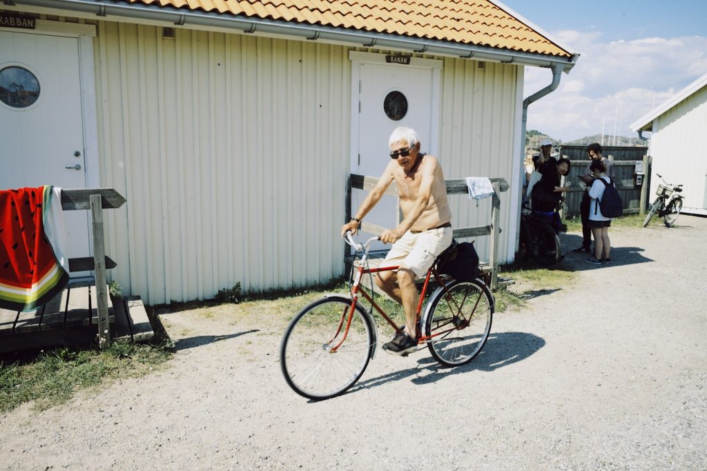 Elderly man rides a bicycle near beach huts