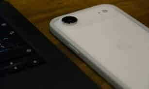 White iPhone with clear case next to laptop