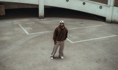 Man in brown hoodie standing on concrete court