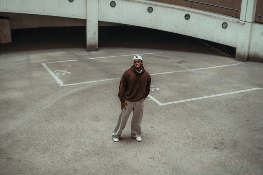 Man in brown hoodie standing on concrete court