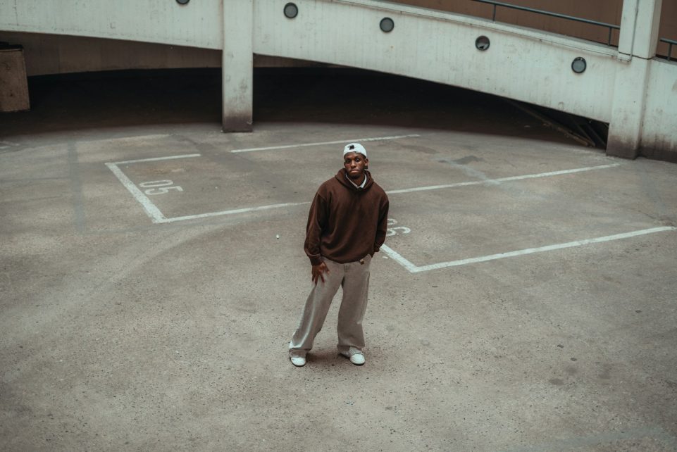 Man in brown hoodie standing on concrete court