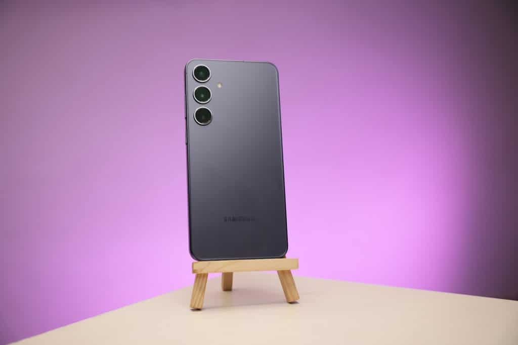 a black cell phone sitting on top of a wooden stand