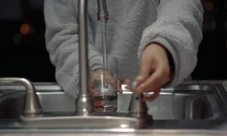 person holding clear glass container