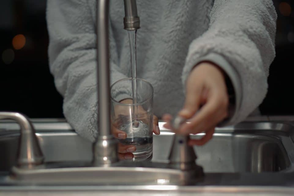 person holding clear glass container