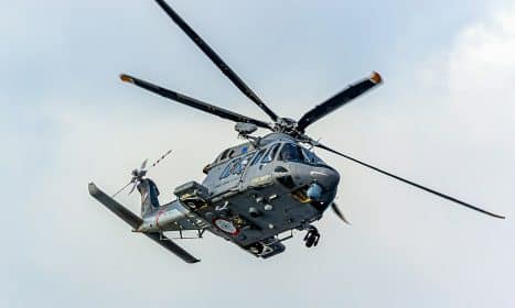 a helicopter flying in the sky with a person standing on the front of it