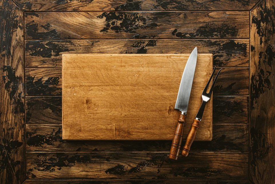 a knife and a board on a wooden surface