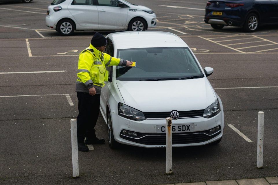 man in yellow jacket standing beside white car