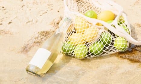 Lemons and a drink on the sand at the beach.