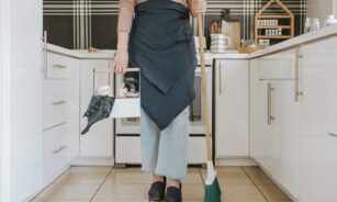 a woman standing in a kitchen holding a broom