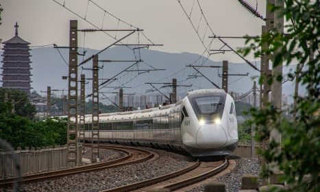 a white train traveling down train tracks next to a forest