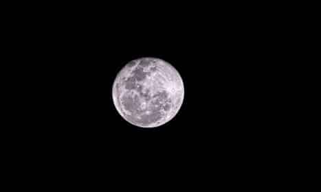 a full moon is seen in the dark sky