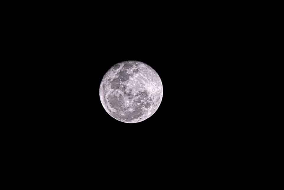 a full moon is seen in the dark sky