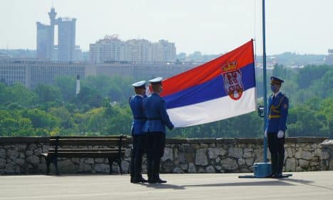 man in black jacket standing near flag of us a during daytime