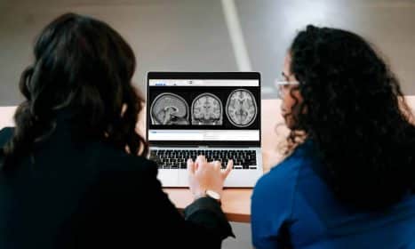 Two women looking at a computer screen with mri images on it