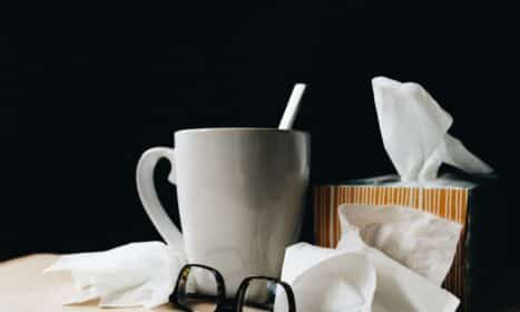 white ceramic mug on white table beside black eyeglasses