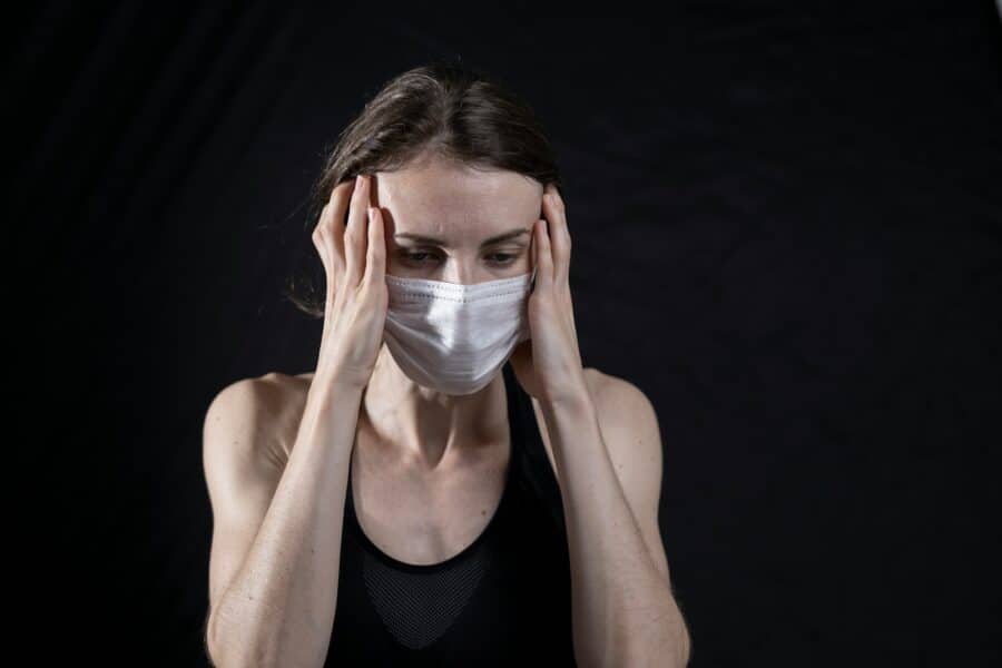 woman in black tank top covering her face with her hands
