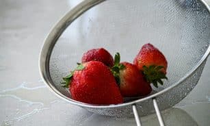 red strawberries in stainless steel strainer