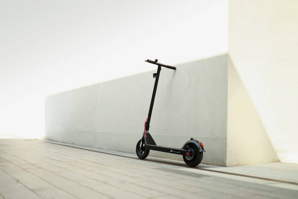 a scooter parked next to a wall on a sidewalk