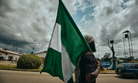 woman in black and white hijab holding green flag