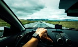 person driving car near vehicle under nimbus cloudes