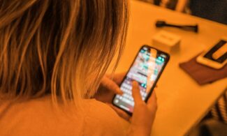 woman in white shirt holding black iphone 4