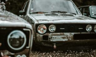 two old cars are parked in a field